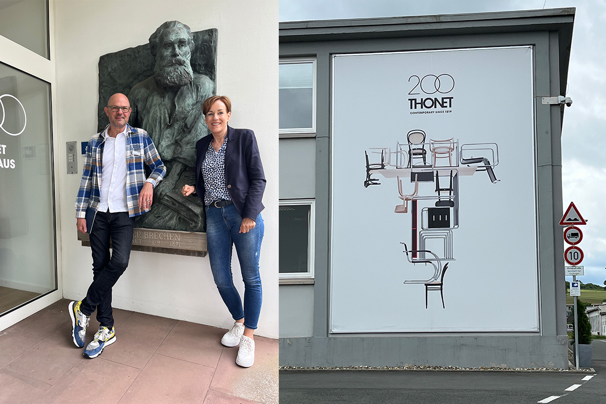 Links stehen zwei Personen vor einem Reliefporträt von Peter Thonet am Eingang des Thonet-Museumsgebäudes und lächeln in die Kamera. Rechts ist eine große Wandgrafik mit stilisierten Stühlen in Kreuzform zu sehen, darüber das Logo „200 Jahre Thonet – Contemporary since 1819“.