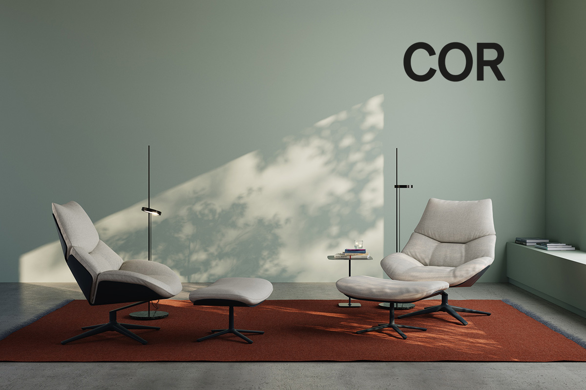 Ein modernes, minimalistisches Lounge-Setup mit zwei COR Shrimp Lounge-Sesseln und passenden Hockern. Die Stühle stehen auf einem rostfarbenen Teppich vor einer hellgrünen Wand, auf der der Markenname "COR" prominent angezeigt wird.