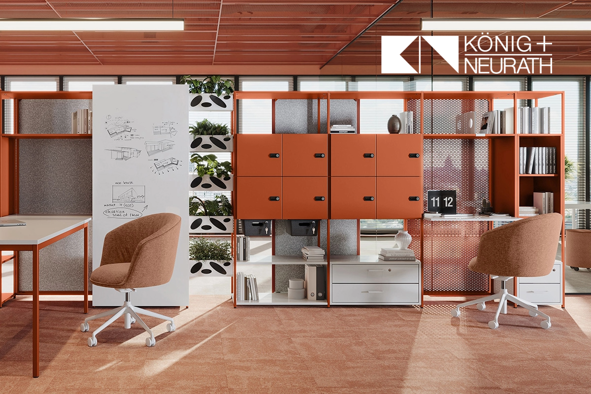 Modern gestalteter Büroraum mit dem modularen Stauraumsystem ACTA.PRO von König + Neurath in warmem Orange, kombiniert mit offenen Regalelementen, Pflanzmodulen und abschließbaren Fächern. Zwei gepolsterte Drehstühle und ein höhenverstellbarer Tisch ergänzen die flexible Arbeitsumgebung.